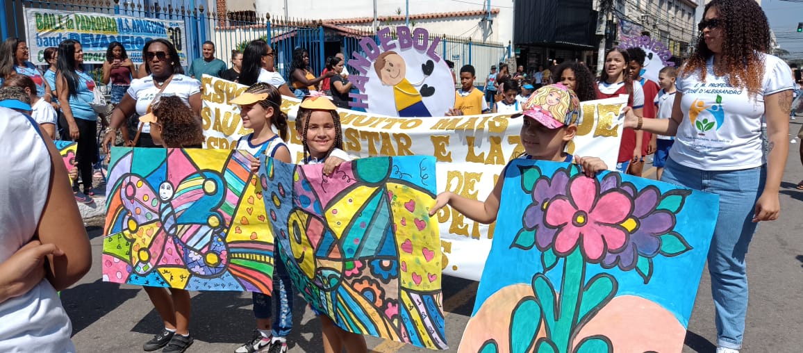 Desfile público com professores e alunos exibindo artes plásticas